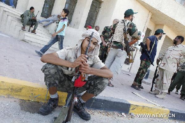 Libyan rebels stand guard outside a bank in Tripoli, Libya, Aug. 29, 2011. Muammar Gaddafi is still a threat to Libya and the world, as his whereabouts remain misty, chief of the executive board of the Libyan National Transitional Council (NTC) Mostafa Abdel Jalil said Monday. [Hamza Turkia/Xinhua]