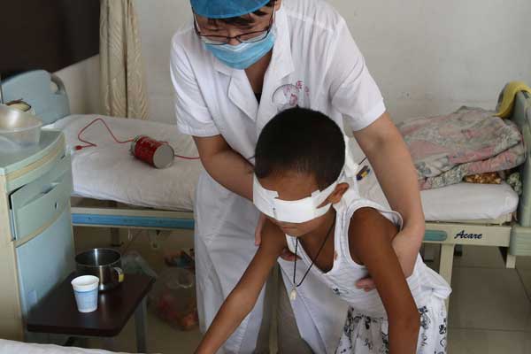 Guo Bin, aided by a doctor at Shanxi Eye Hospital in Taiyuan, tries to walk during a rehabilitation training program that started on Sunday.[ZHANG YUN / CHINA NEWS SERVICE]